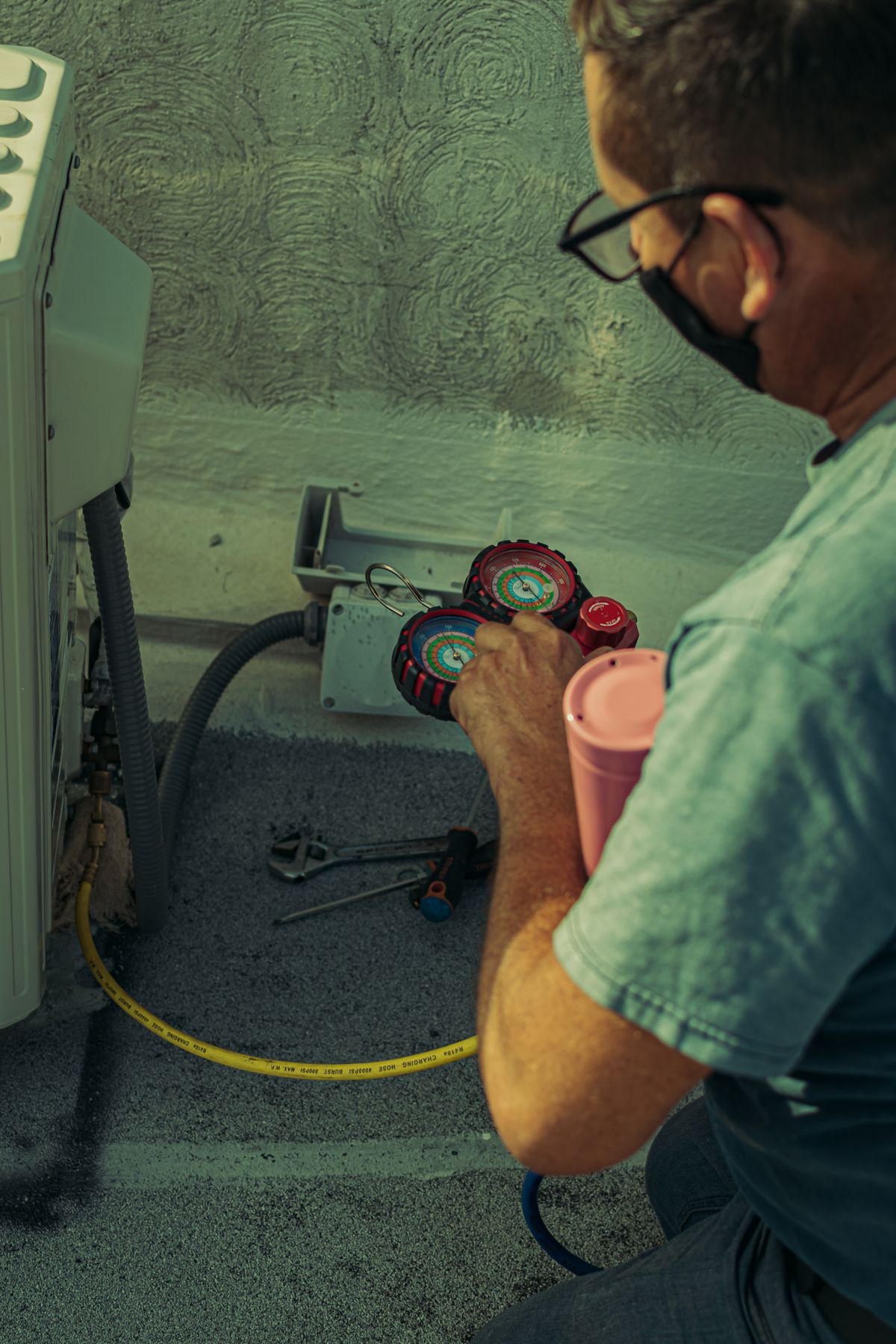 An HVAC technician checking and repairing an outdoor air conditioning unit